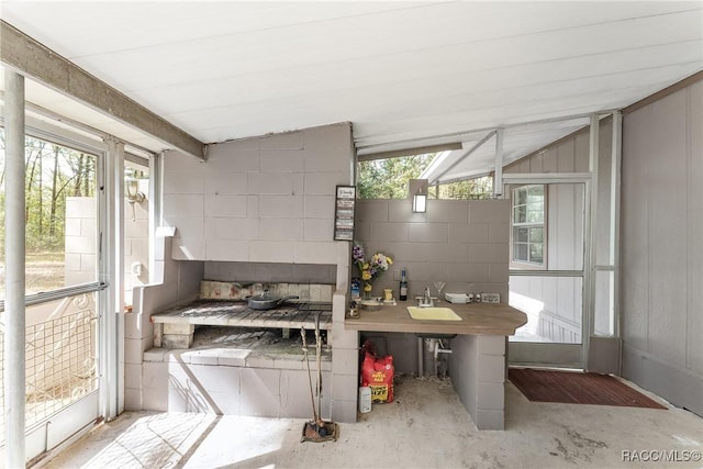 kitchen featuring unfinished concrete flooring and concrete block wall