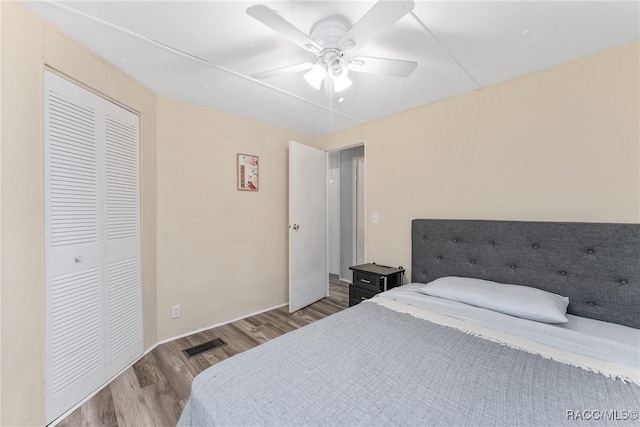 bedroom with a closet, visible vents, ceiling fan, and wood finished floors