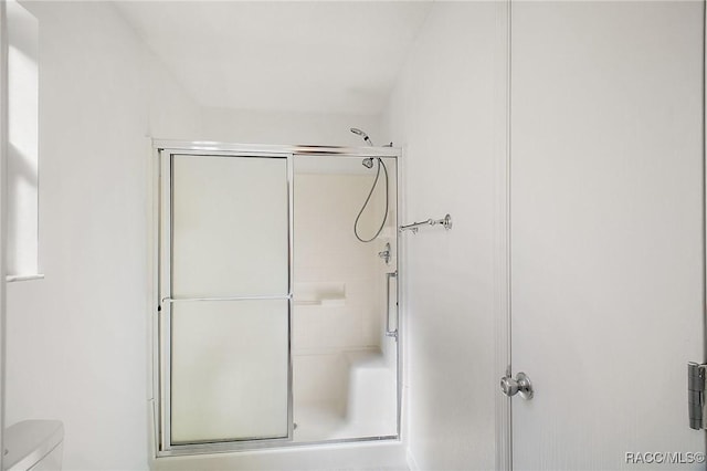 bathroom featuring toilet and a shower with shower door