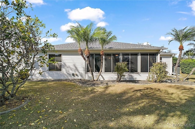 back of property with a sunroom and a lawn