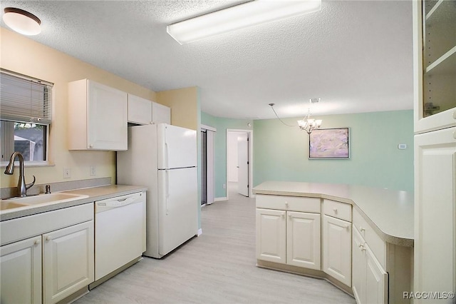 kitchen with white appliances, an inviting chandelier, sink, light hardwood / wood-style flooring, and white cabinetry