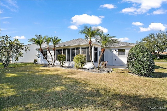 rear view of property featuring a lawn and a sunroom