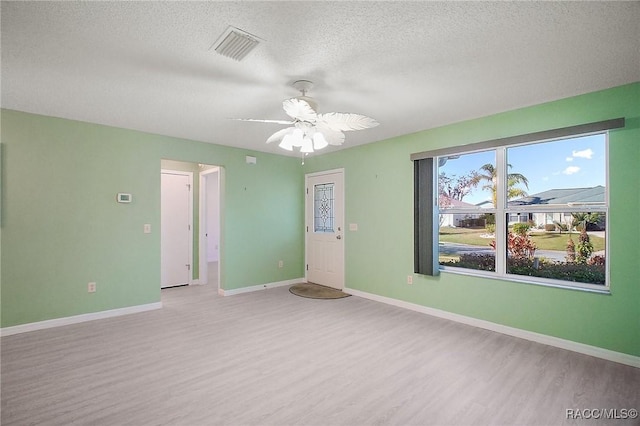 empty room with a textured ceiling, light hardwood / wood-style floors, and ceiling fan