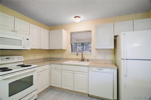 kitchen featuring light wood-type flooring, a textured ceiling, white appliances, sink, and white cabinets