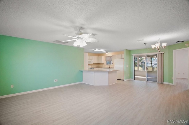 unfurnished living room with ceiling fan with notable chandelier, a textured ceiling, and light hardwood / wood-style flooring