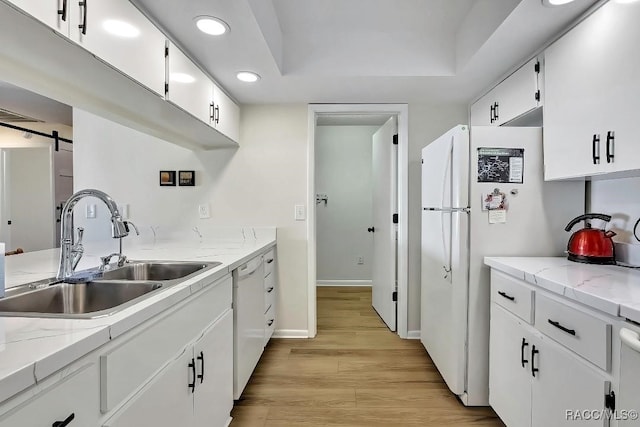 kitchen with sink, white appliances, a barn door, and white cabinets