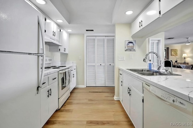 kitchen featuring sink, light hardwood / wood-style flooring, white appliances, light stone countertops, and white cabinets