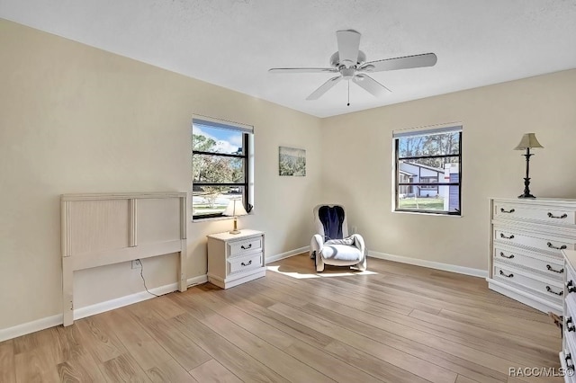 living area with ceiling fan, a healthy amount of sunlight, and light hardwood / wood-style floors