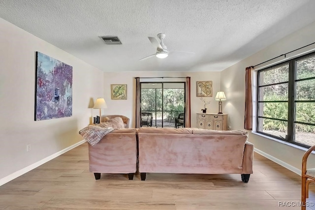 living room featuring ceiling fan, a textured ceiling, and light wood-type flooring