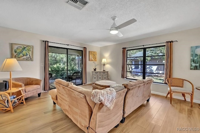 living room featuring a textured ceiling, ceiling fan, and light hardwood / wood-style floors