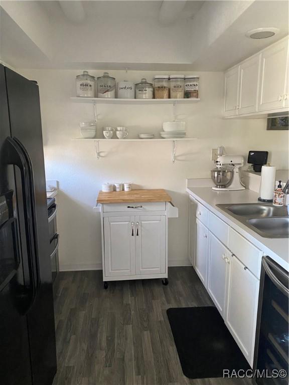 kitchen featuring white cabinetry, light countertops, a sink, and black fridge