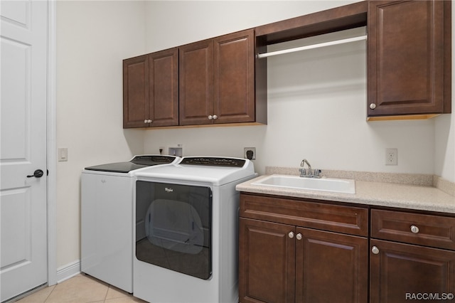 laundry room with washer and dryer, light tile patterned flooring, cabinets, and sink