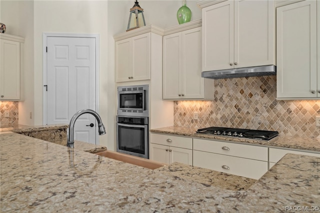 kitchen with appliances with stainless steel finishes, backsplash, and light stone counters