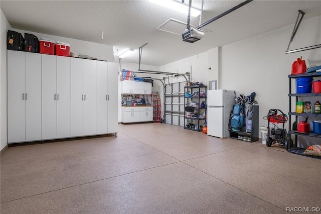 garage featuring white refrigerator and a garage door opener