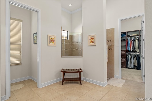 corridor featuring crown molding and light tile patterned floors