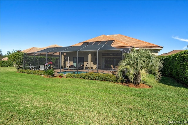 rear view of house featuring a lawn and glass enclosure