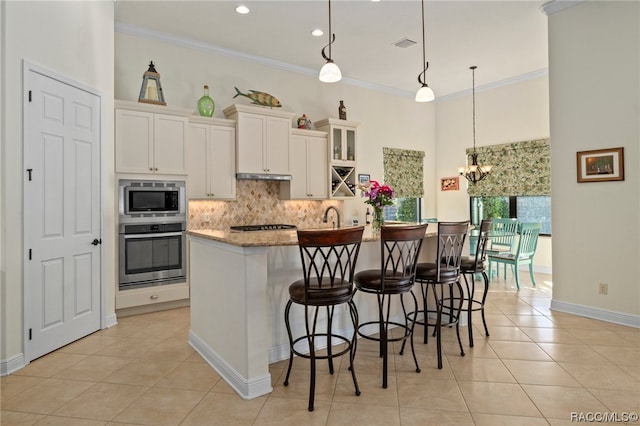 kitchen featuring appliances with stainless steel finishes, an inviting chandelier, a breakfast bar area, and crown molding