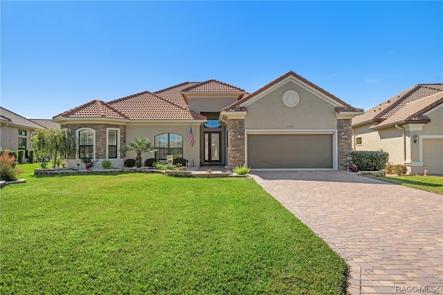 mediterranean / spanish home featuring a garage and a front lawn