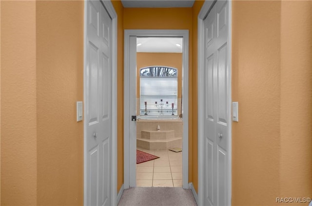hall with carpet floors, baseboards, and tile patterned flooring