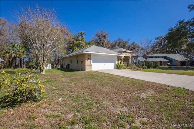 view of side of property featuring driveway, a lawn, brick siding, an attached garage, and stucco siding