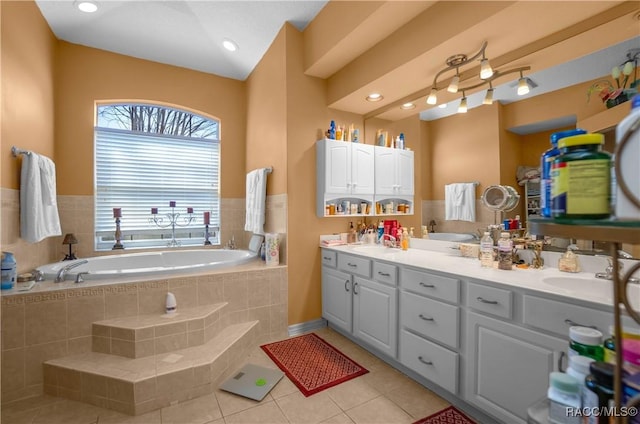 bathroom with a sink, tile patterned floors, double vanity, and a bath