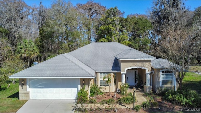 ranch-style home featuring a garage, stucco siding, and driveway