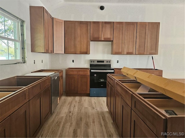 kitchen featuring light wood finished floors, appliances with stainless steel finishes, and brown cabinetry