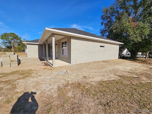 view of property exterior featuring roof with shingles, a patio area, and stucco siding