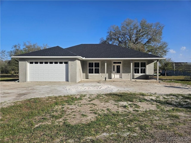 view of front of property featuring driveway, roof with shingles, an attached garage, and stucco siding