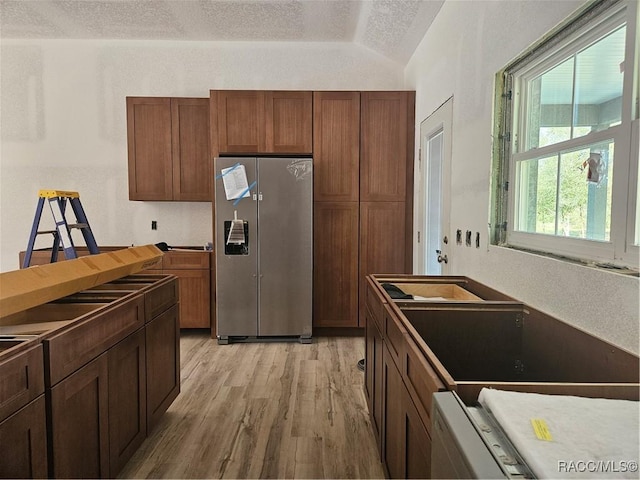 kitchen with lofted ceiling, light wood-style floors, stainless steel refrigerator with ice dispenser, and a textured ceiling