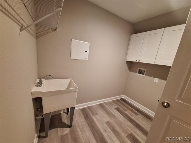 clothes washing area with cabinets, hookup for a washing machine, and light hardwood / wood-style floors