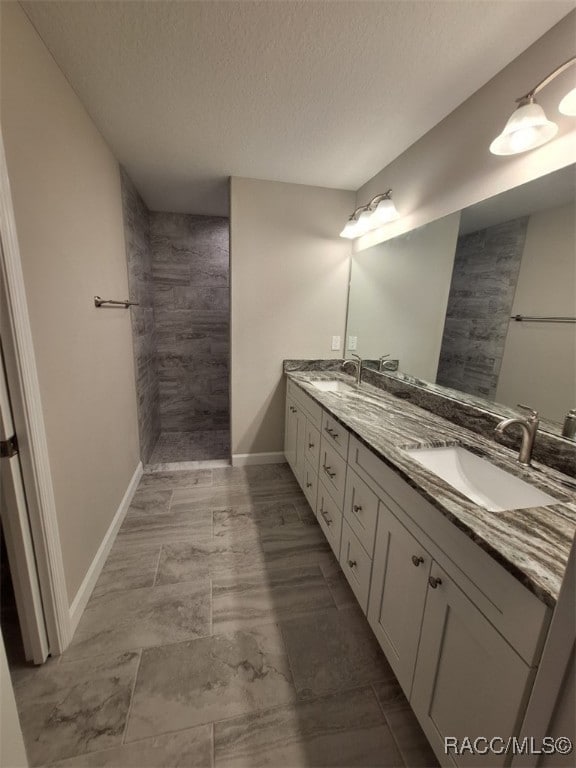 bathroom featuring vanity, a textured ceiling, and tiled shower