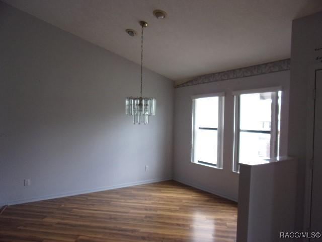 6337 W Lexington Dr, Crystal River, FL 34429 - spare room with dark wood-type flooring, a notable chandelier, baseboards, and lofted ceiling