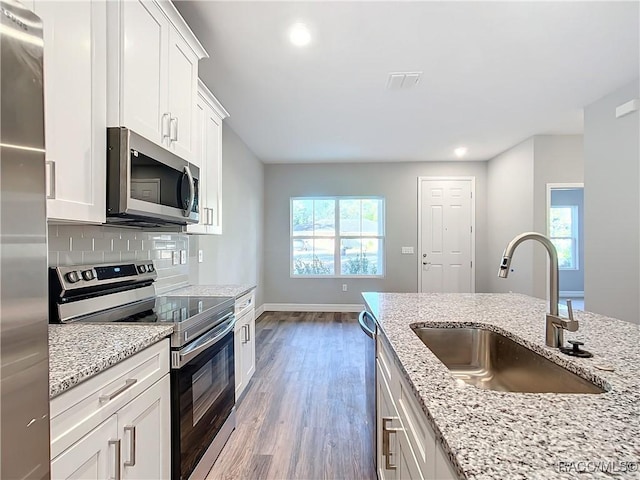 kitchen featuring sink, white cabinetry, light stone counters, appliances with stainless steel finishes, and decorative backsplash