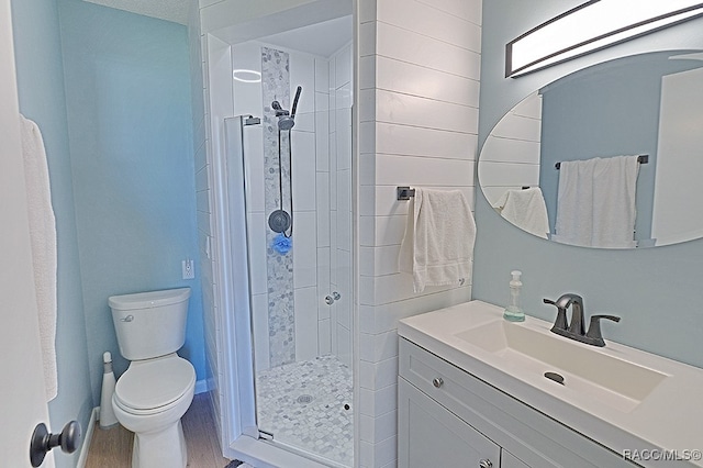 bathroom with tiled shower, vanity, hardwood / wood-style flooring, and toilet