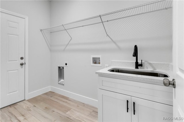 clothes washing area featuring electric dryer hookup, baseboards, washer hookup, a sink, and light wood-type flooring