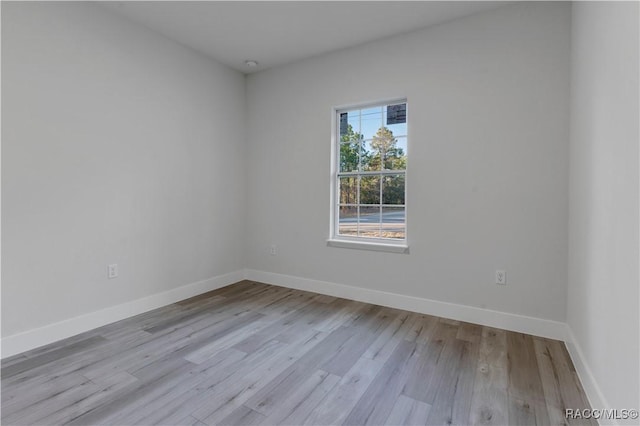 spare room with baseboards and light wood-style floors