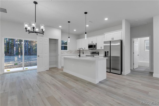 kitchen with appliances with stainless steel finishes, light countertops, hanging light fixtures, visible vents, and white cabinetry