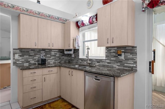 kitchen featuring dark stone counters, light brown cabinetry, and dishwasher