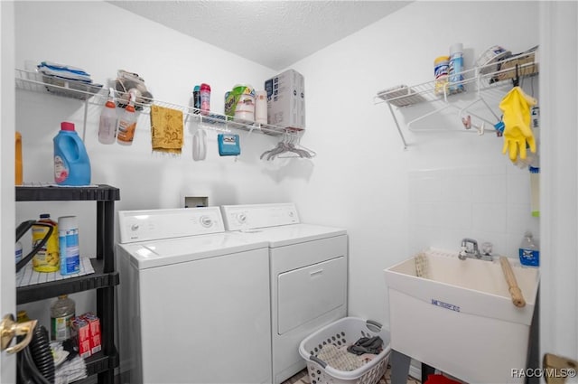 washroom featuring sink, washing machine and clothes dryer, and a textured ceiling