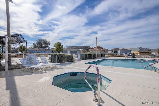 view of swimming pool featuring a hot tub and a patio