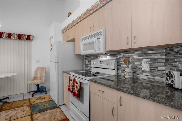 kitchen with dark stone countertops, light brown cabinets, light tile patterned floors, white appliances, and decorative backsplash