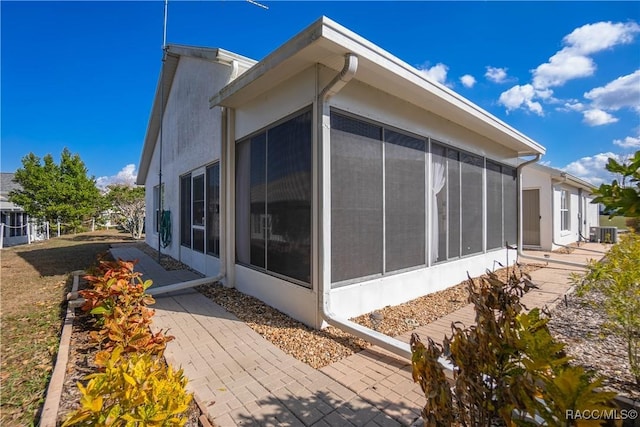 view of home's exterior with cooling unit, a sunroom, and a patio