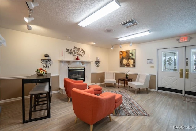 living room featuring track lighting, wood-type flooring, a fireplace, and a textured ceiling