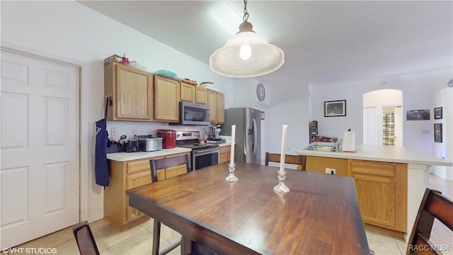 kitchen with a kitchen island, decorative light fixtures, light tile patterned flooring, and appliances with stainless steel finishes