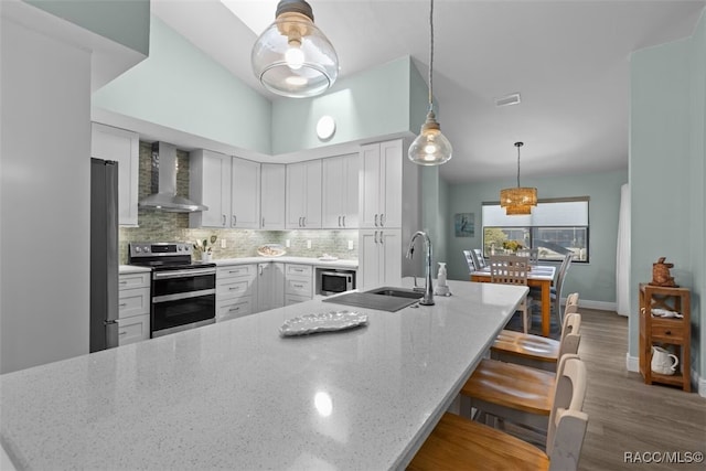 3945 N Timucua Pt, Crystal River, FL 34428 - kitchen with wood finished floors, a sink, wall chimney exhaust hood, backsplash, and appliances with stainless steel finishes