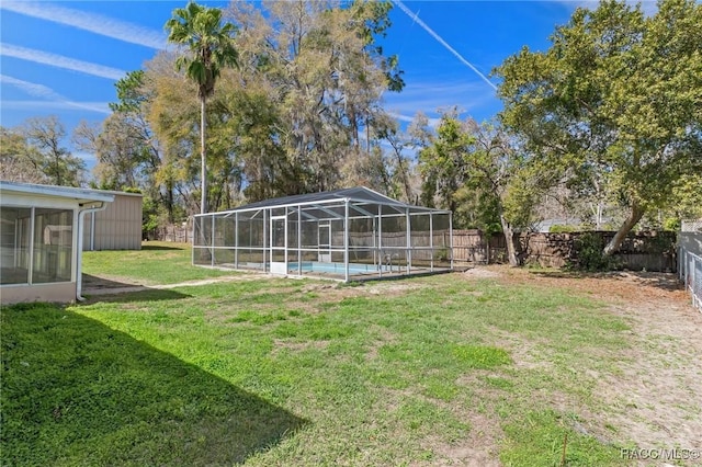 view of yard featuring glass enclosure, a fenced backyard, and a fenced in pool