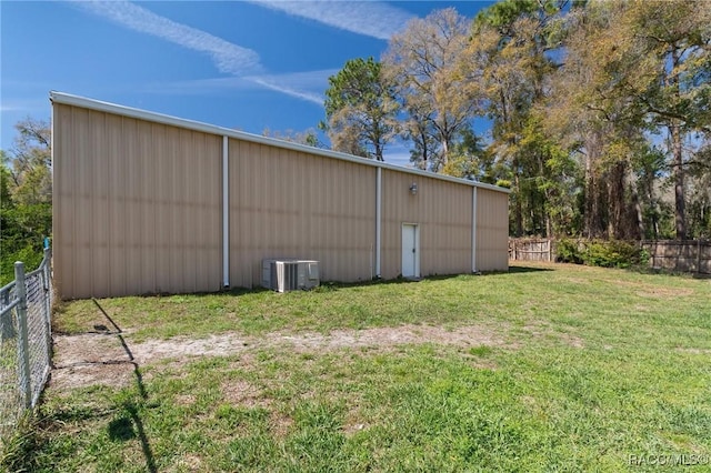 view of pole building featuring central air condition unit, fence, and a yard