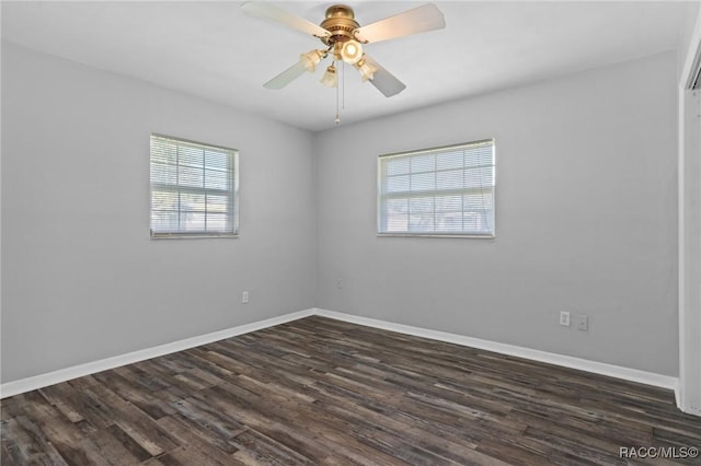 unfurnished room with dark wood finished floors, a ceiling fan, and baseboards