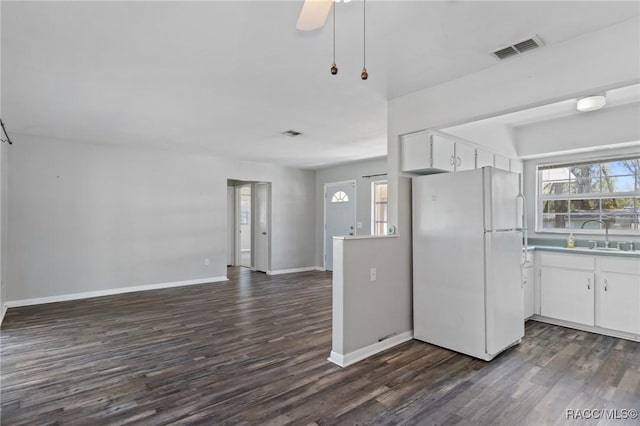 kitchen featuring visible vents, dark wood-style floors, freestanding refrigerator, white cabinetry, and a sink